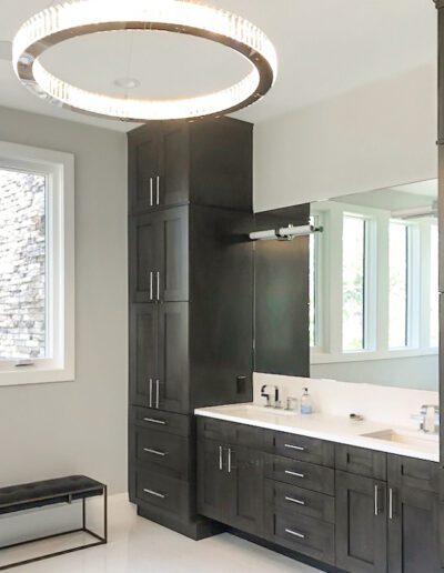 Modern bathroom interior with dark wooden cabinetry and a circular light fixture.