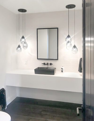 Modern bathroom interior with a floating vanity, rectangular mirror, and pendant lights.